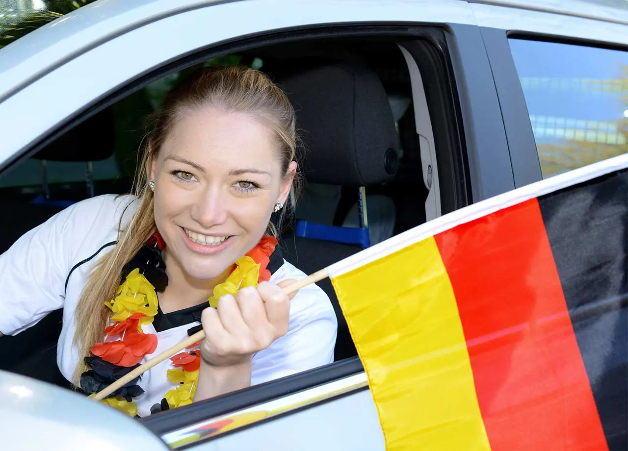 Frau im Auto mit einer Deutschlandfahne.